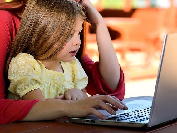 Kind mit Mutter vor einem Laptop